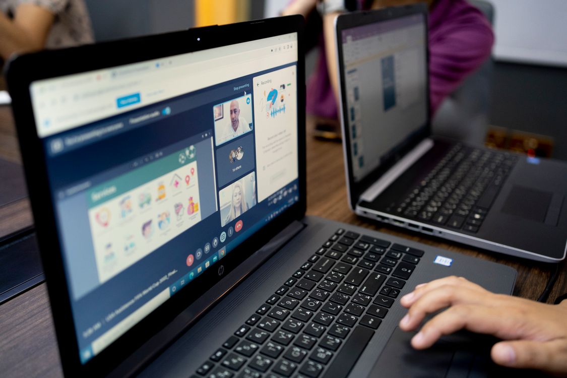 Laptop z otwartą wideokonferencją na drewnianym stole