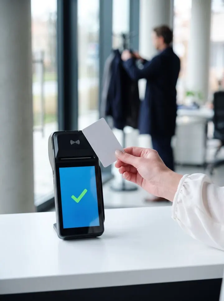 Pracownica przykłada kartę do terminala NFC RCPonline, na ekranie zielony znak potwierdzenia